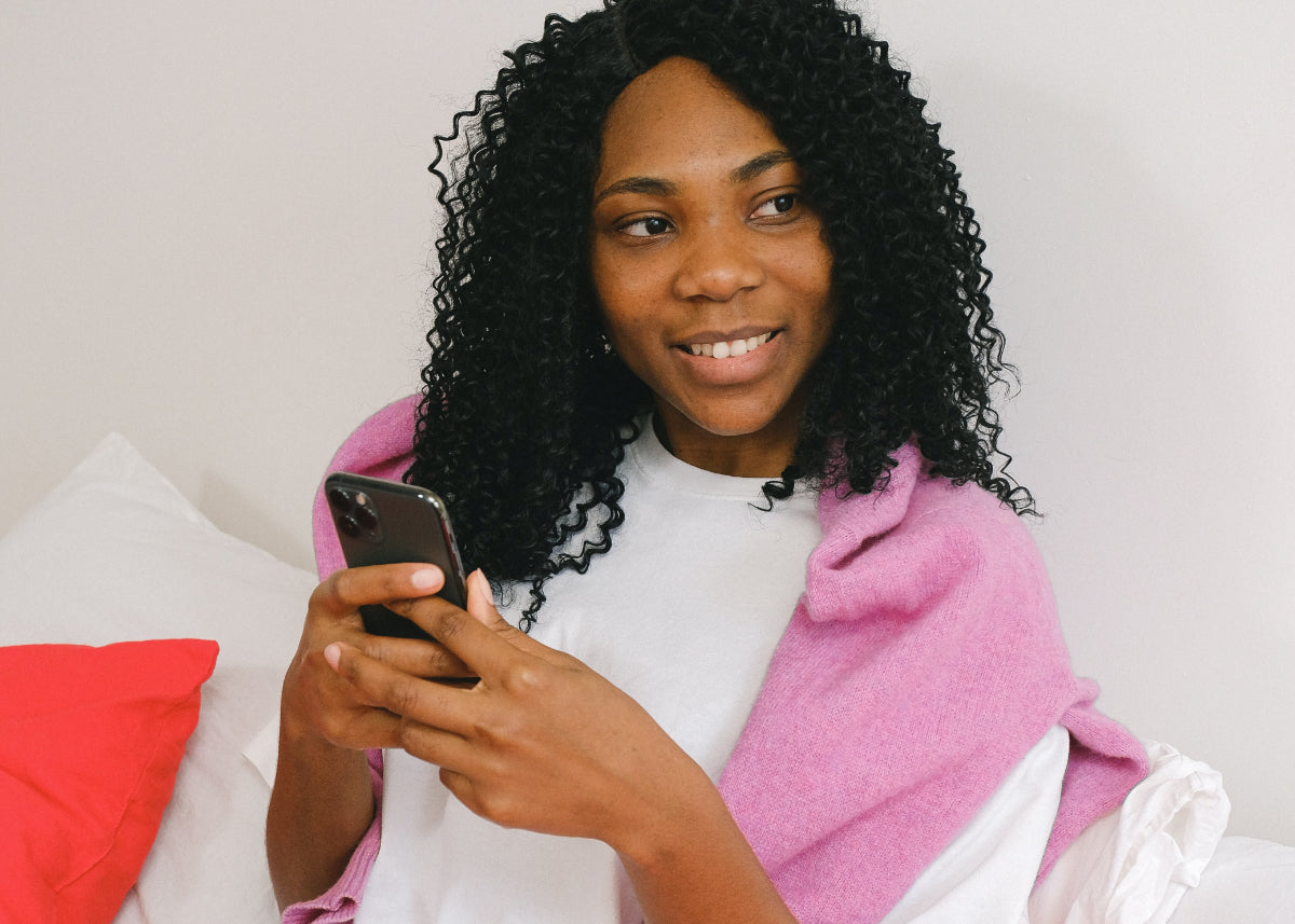 Woman types on a mobile phone, looking off to her left