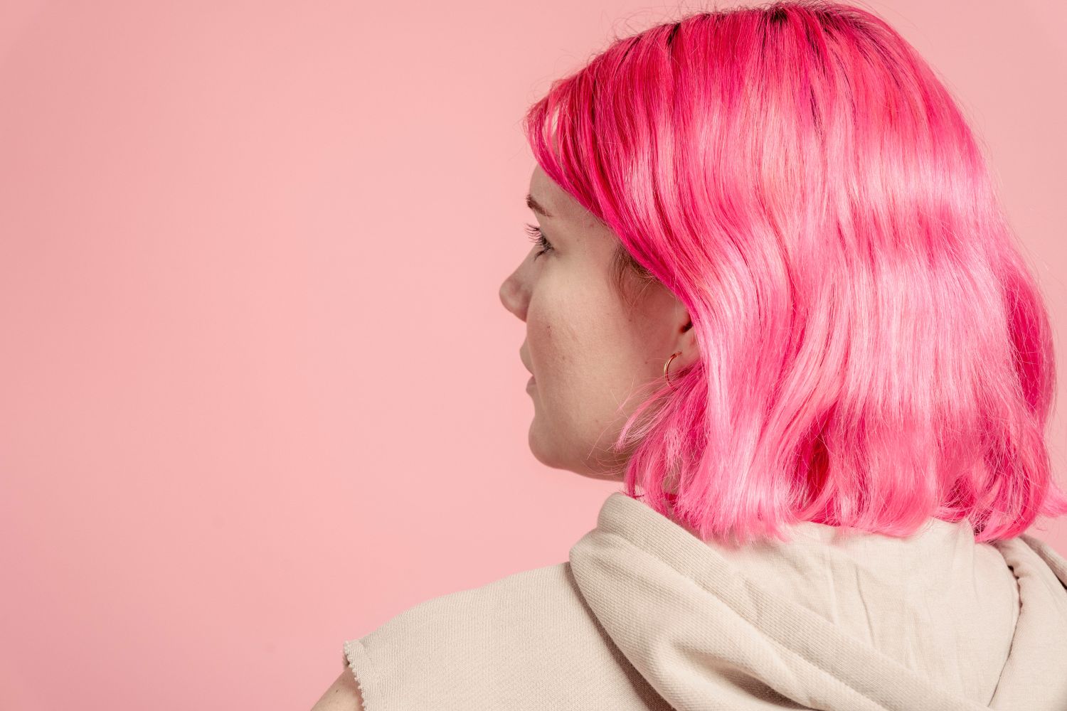 A young woman with pink hair has her back turned to the camera