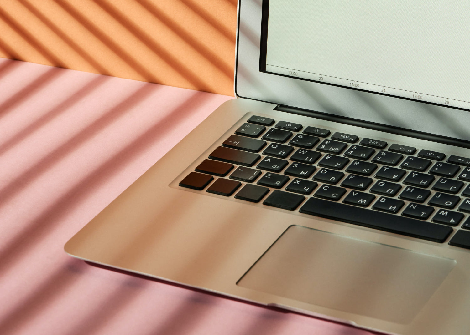 A laptop sits against a pastel-colored backdrop