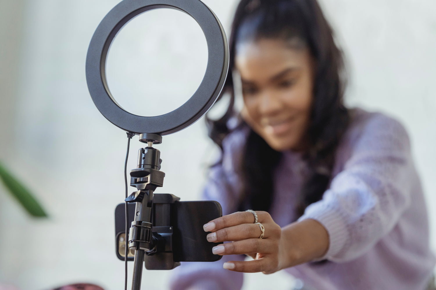 A woman sets up a camera and ring light to shoot a selfie