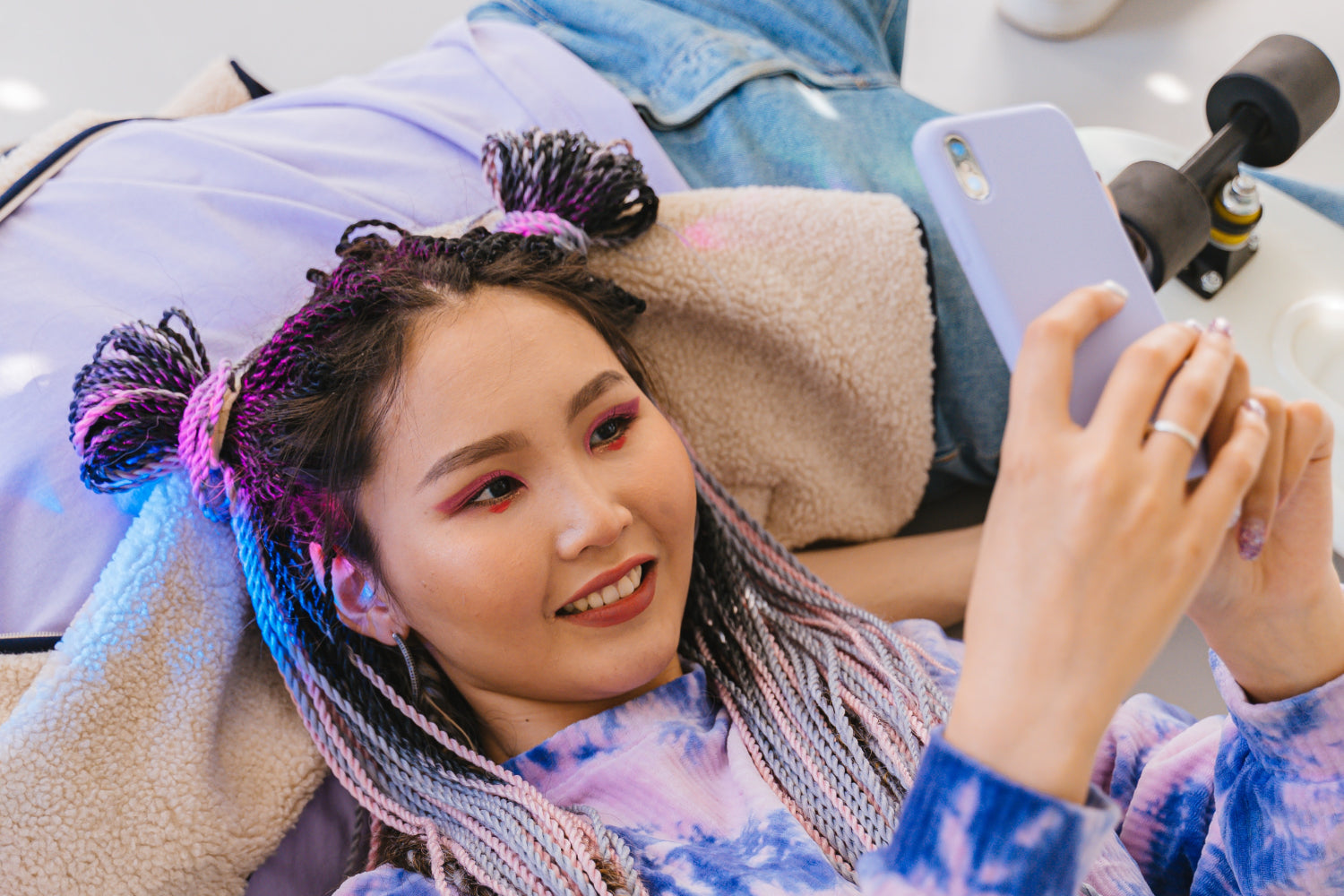 A young woman takes a selfie while laying with her head resting on a friend