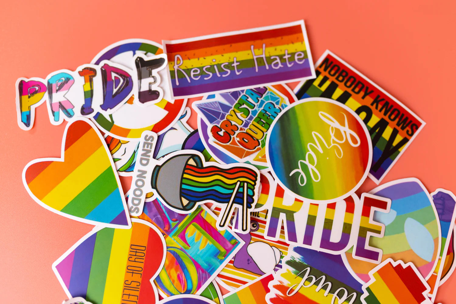 A batch of LGBTQ+ stickers in a pile on a table