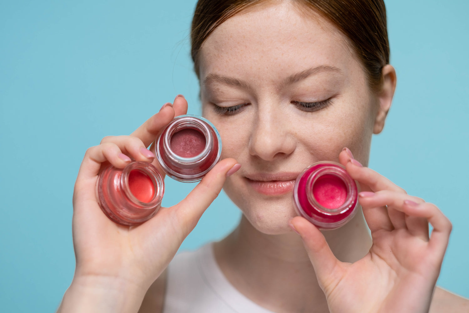 Woman holds three tinted lip balms close to her face