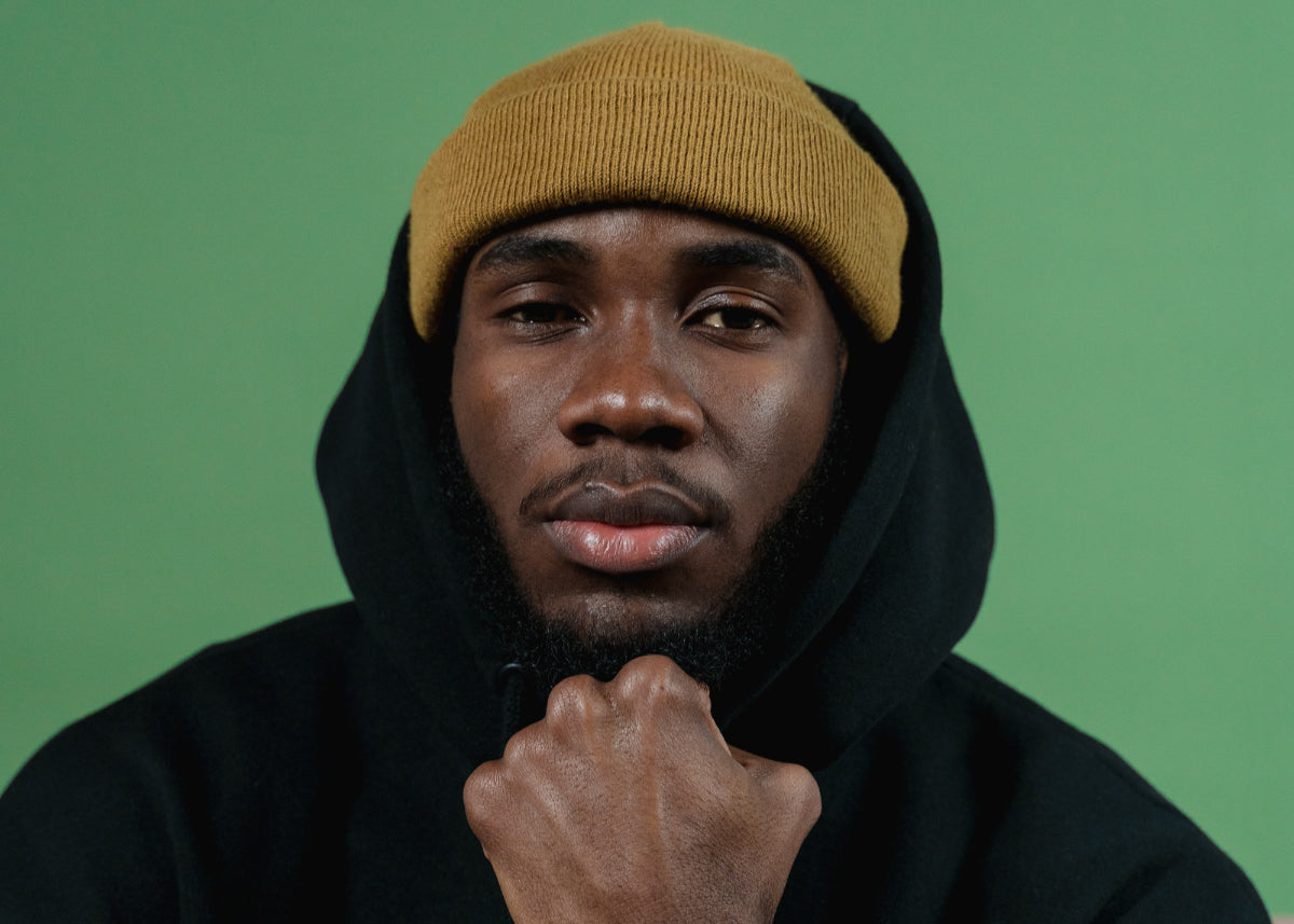 Man in a beanie in front of a green screen