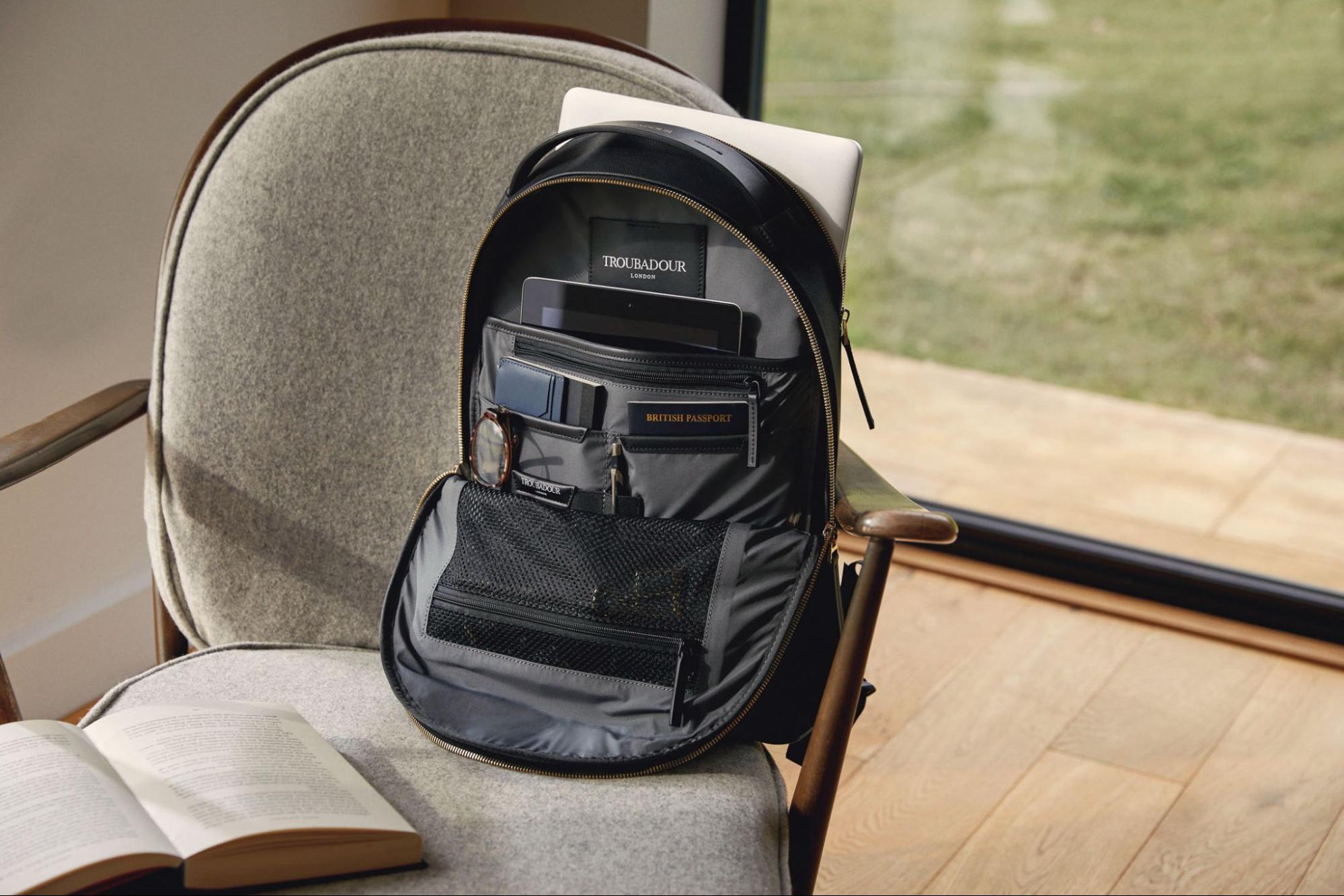 A Troubadour brand front-zip backpack is open revealing its contents and compartments.