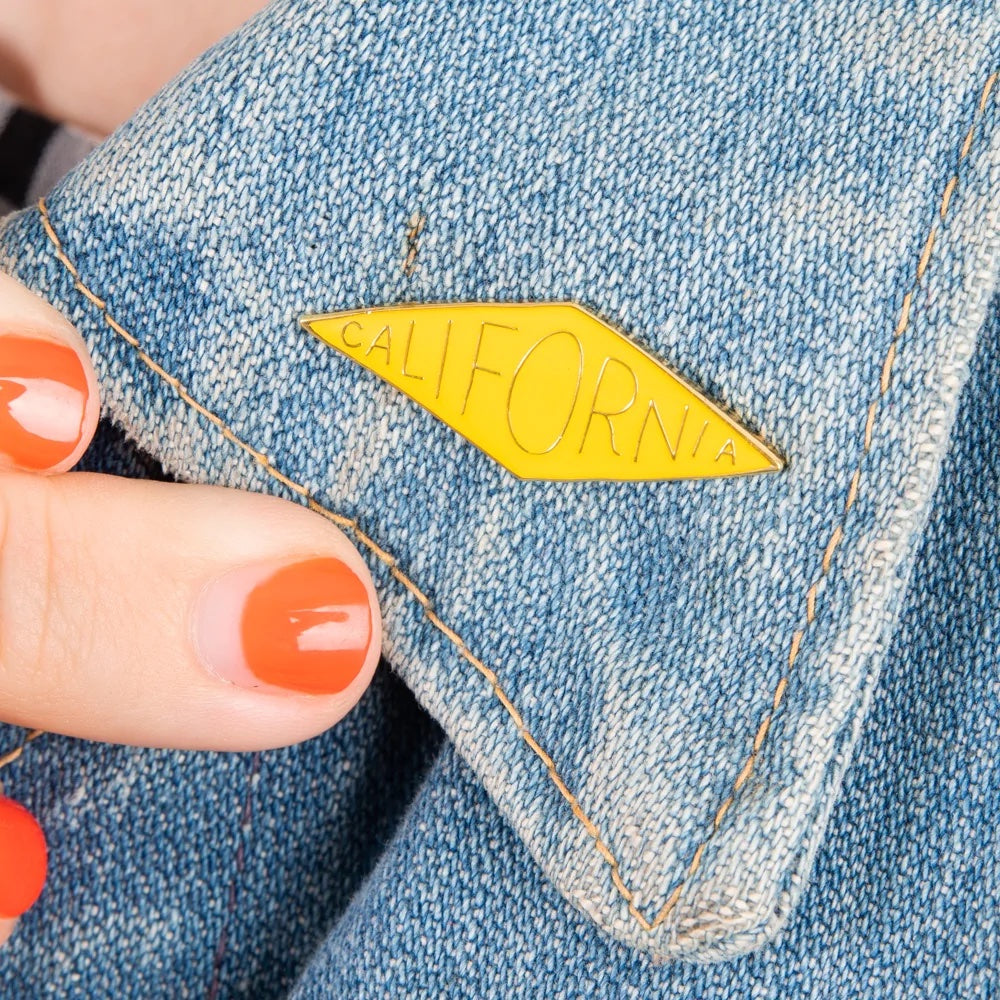 A close up of a denim lapel with a pin that says California