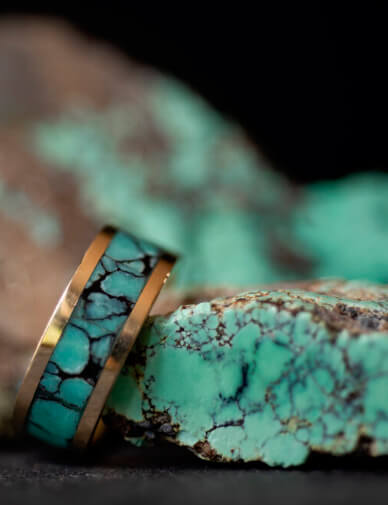 A turquoise ring rests against a raw turquoise rock