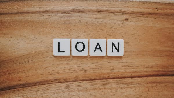 Loan spelled in Scrabble letters on a wood table.