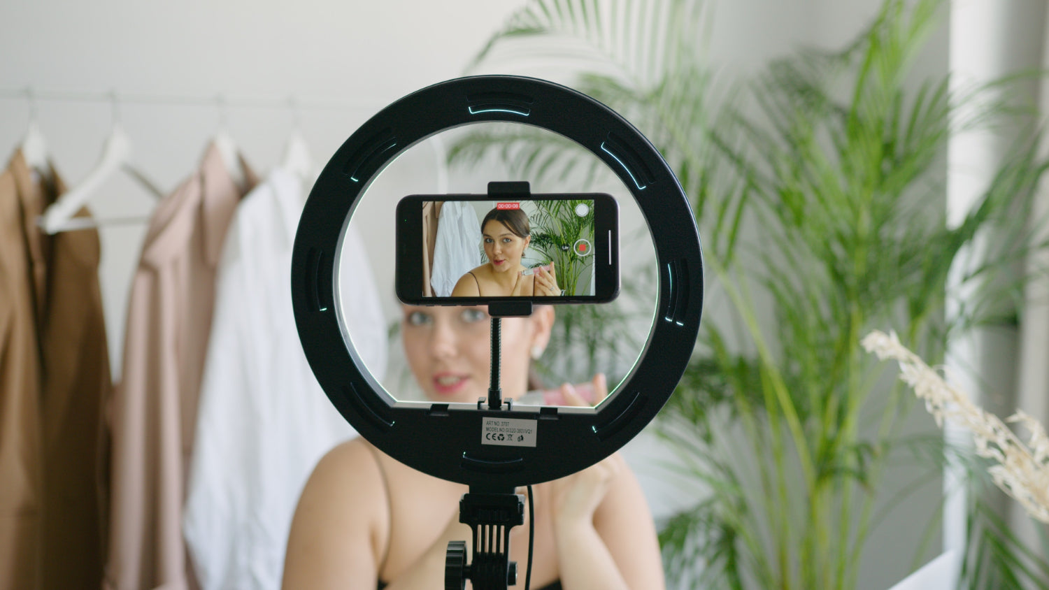 A person records a video of themselves using a phone and ring light