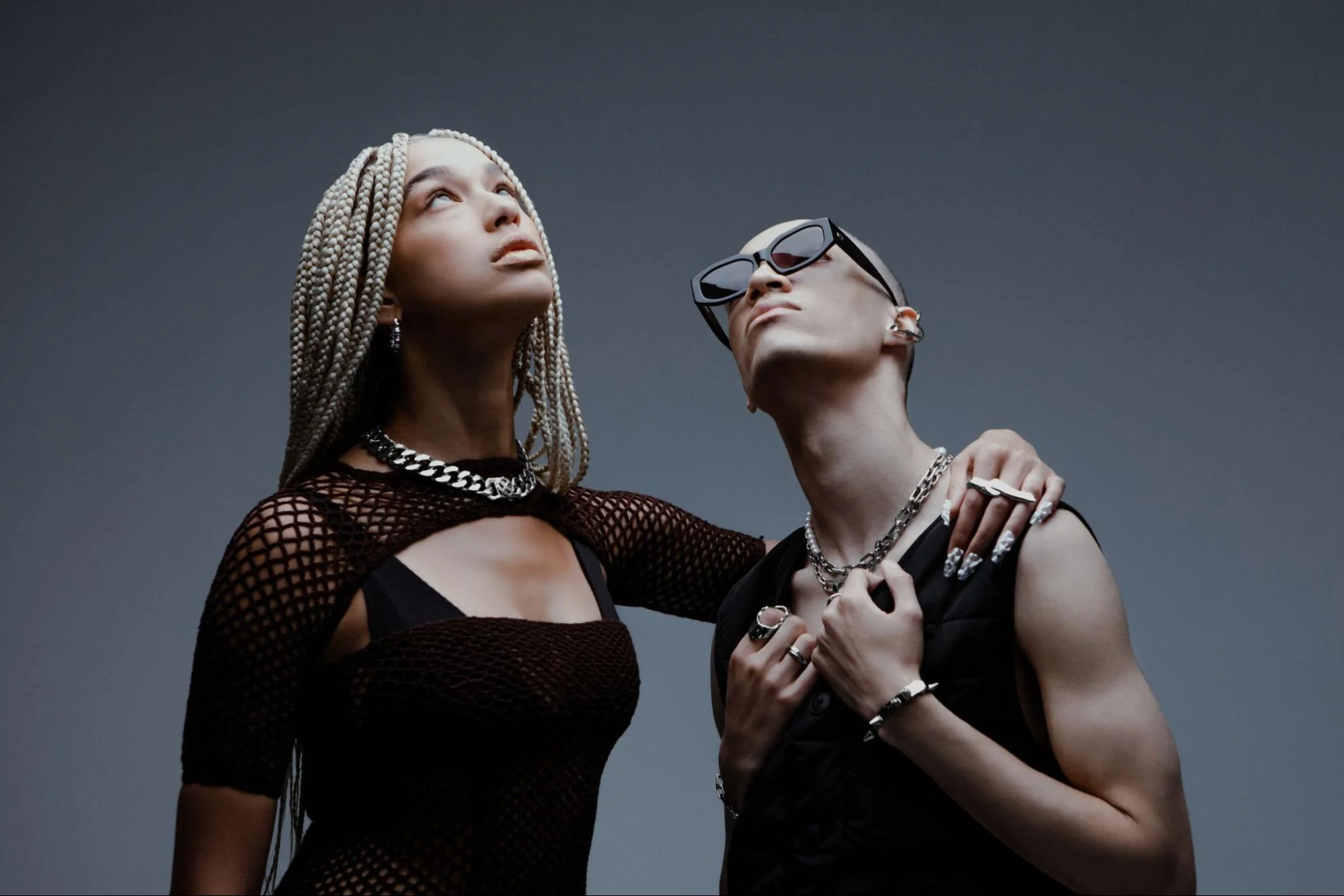 Two models look upward while wearing Vitaly accessories and jewelry and black clothing.