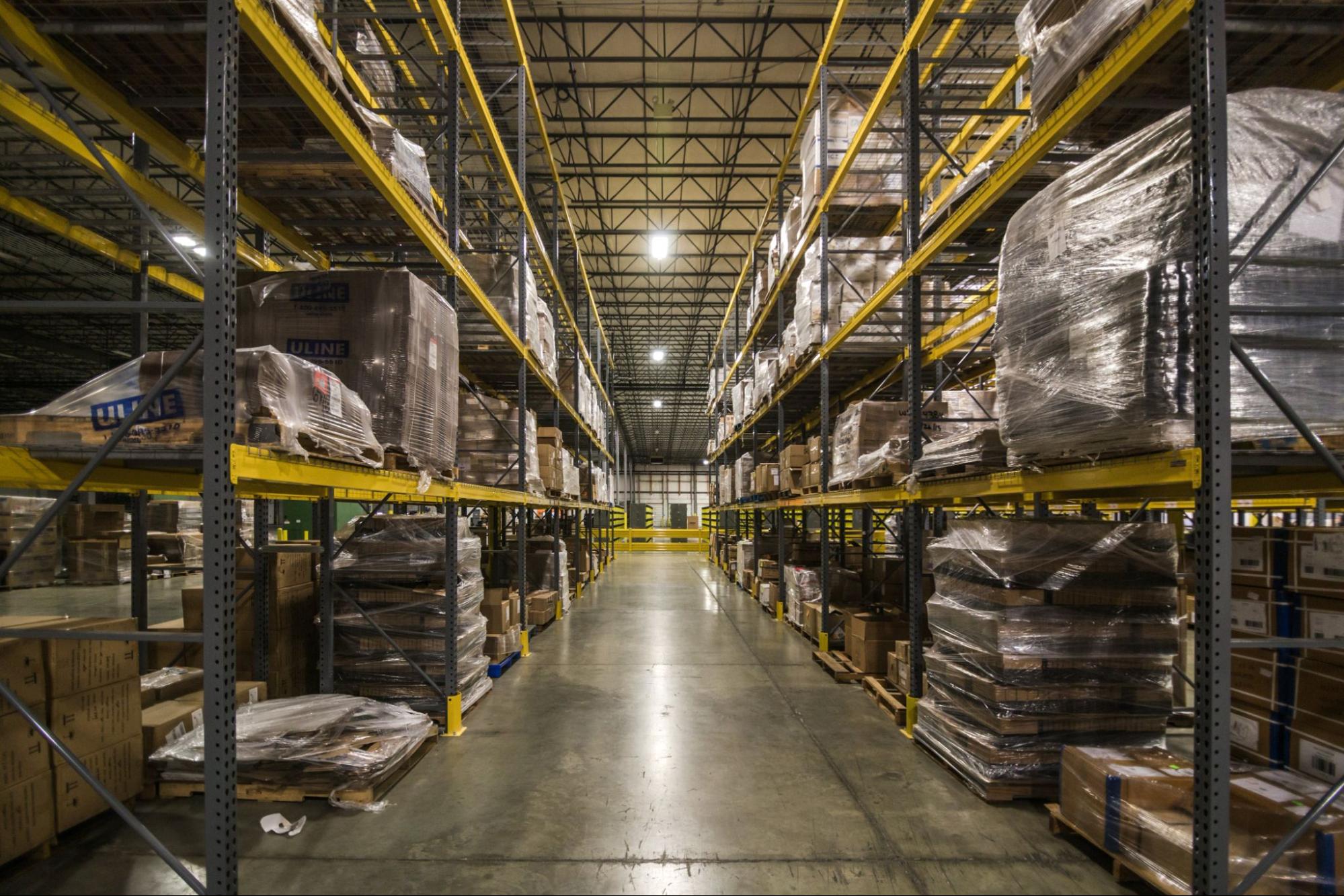 A large warehouse filled with floor-to-ceiling shelves containing pallets and boxes.