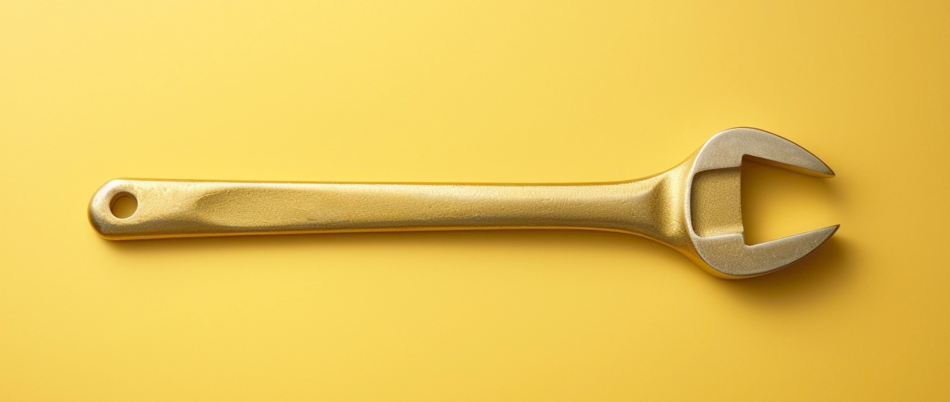 A gold wrench on a yellow background.