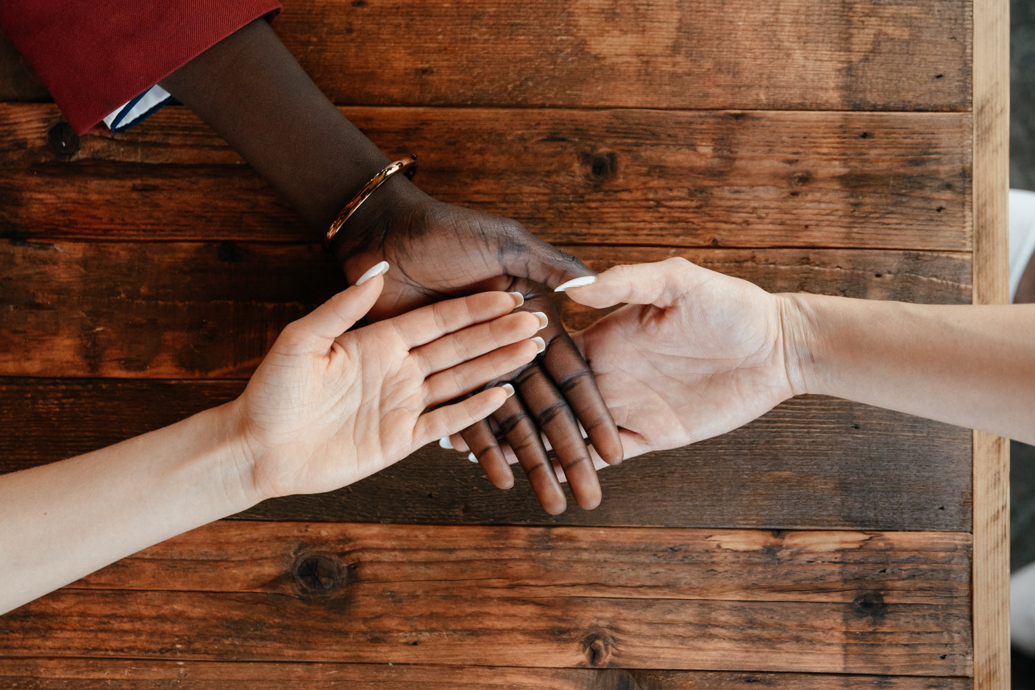 Three people's hand meet in the middle of the frame