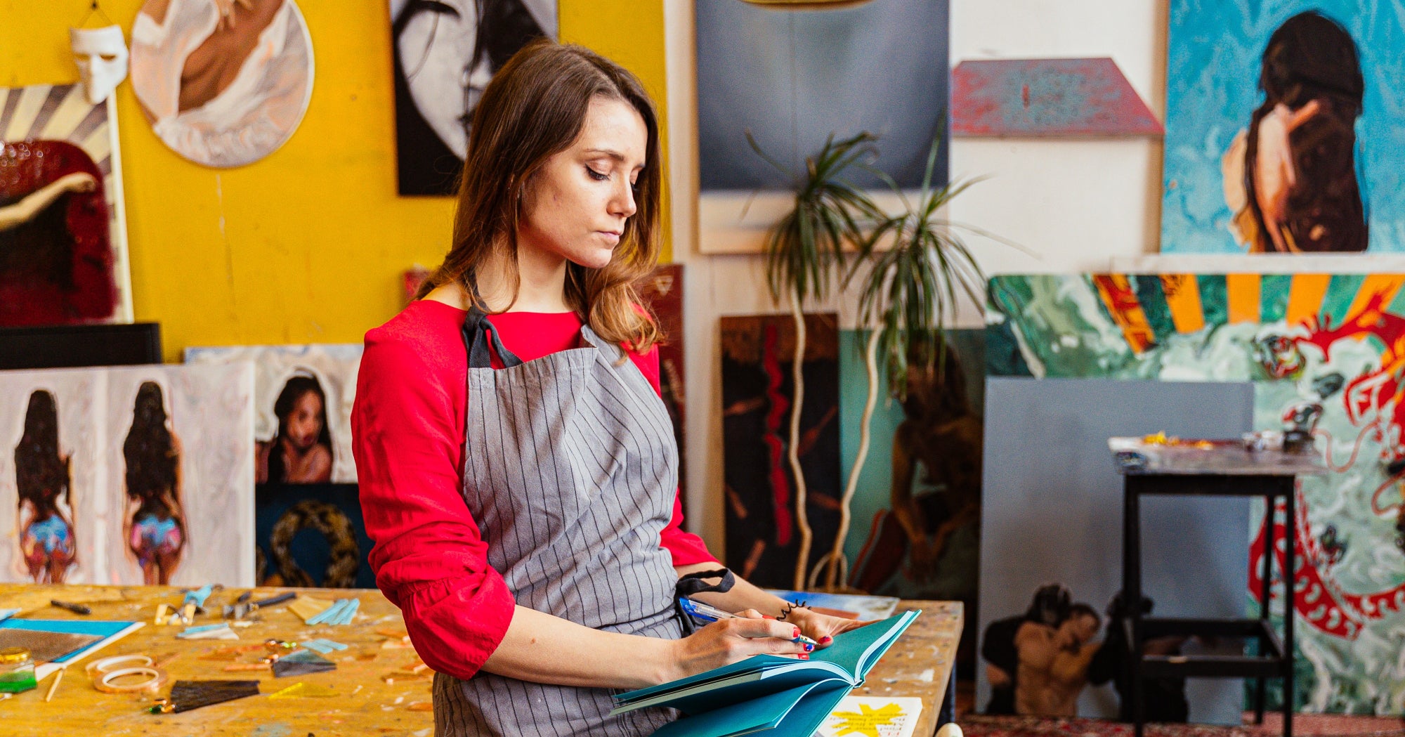 Woman writes in a journal against a backdrop of art