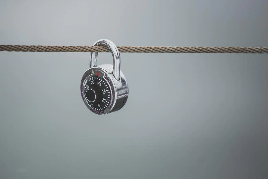 A combination lock is suspended on a wire