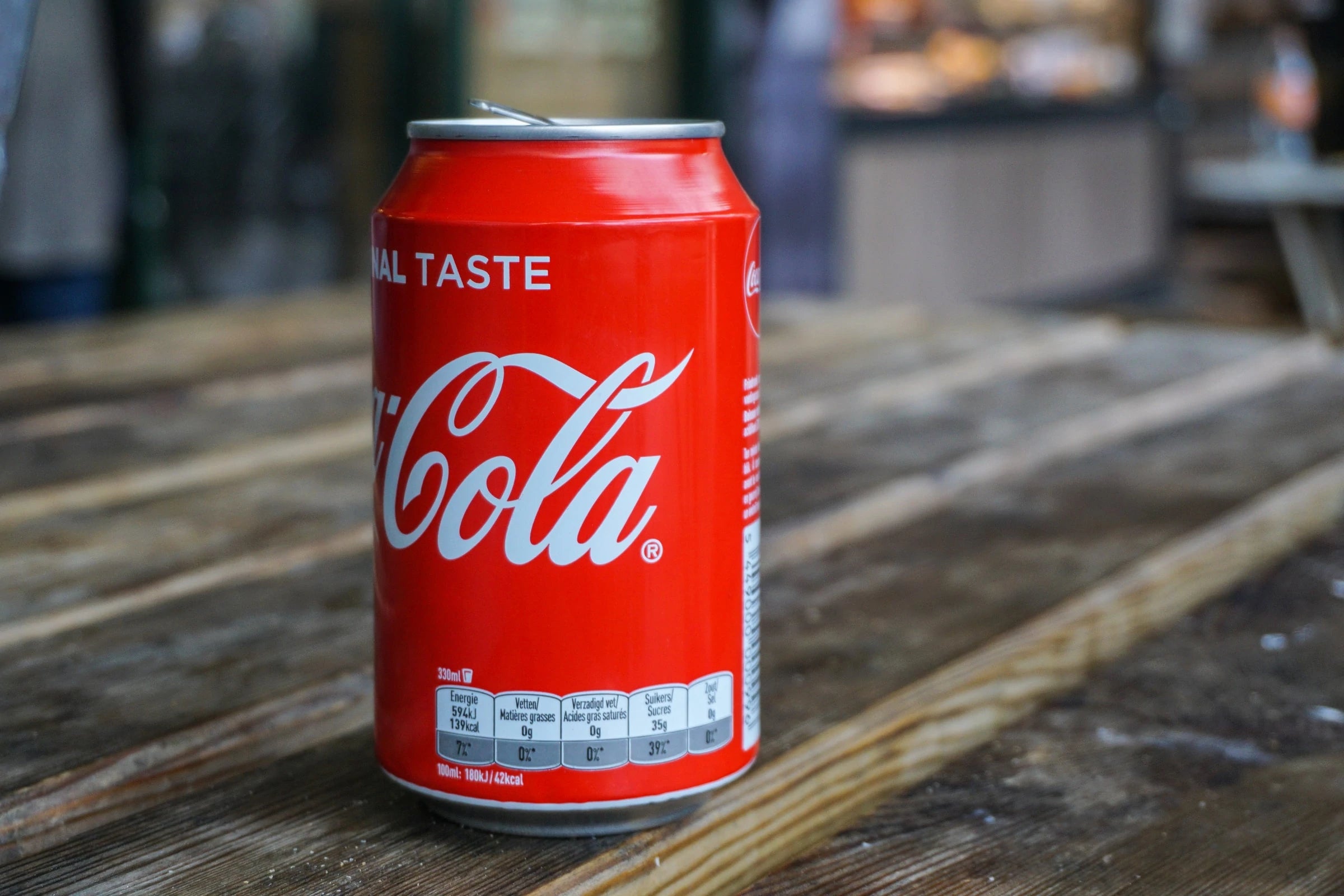 Coca Cola can sitting on a wooden picnic table, turned to show registered trademark symbol