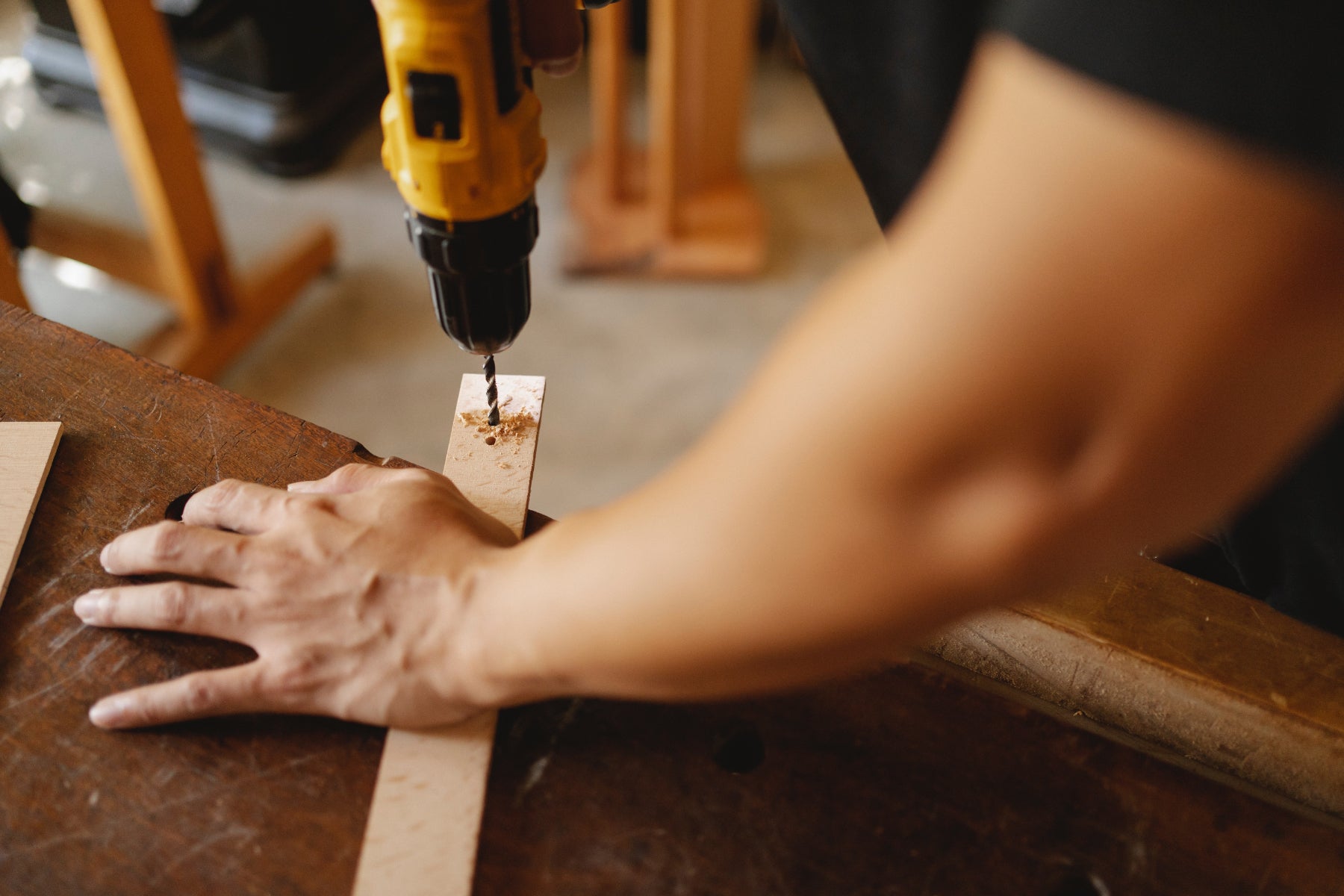 Close up of a person's hands using a drill to make a hole on a piece of wood