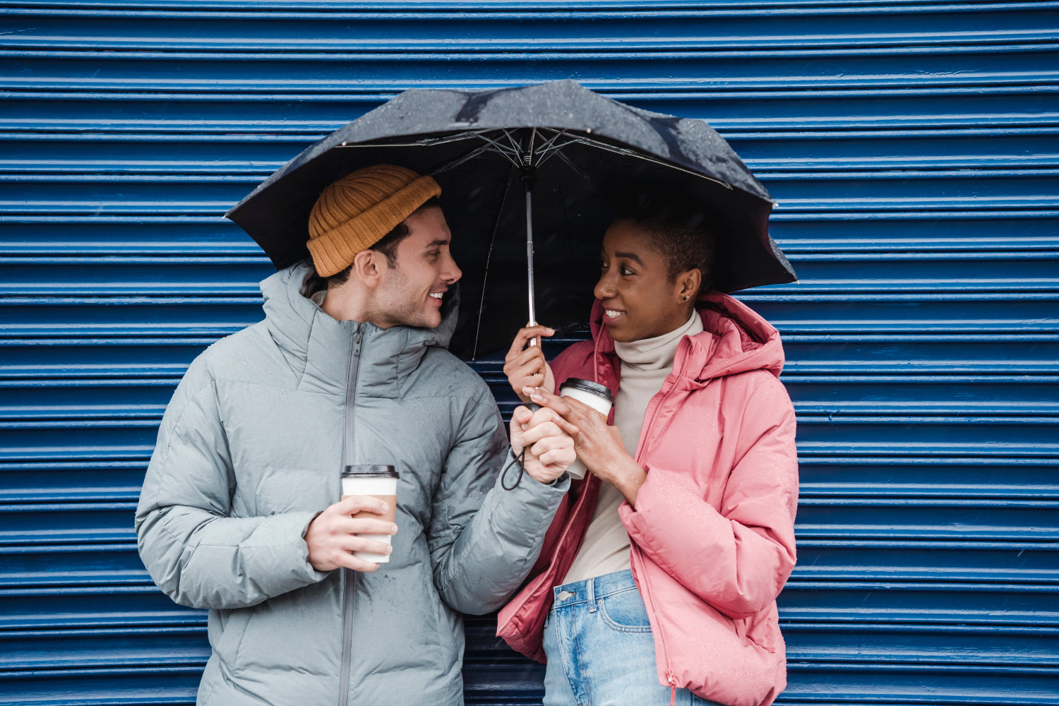 Two people enjoy coffee under an umbrella