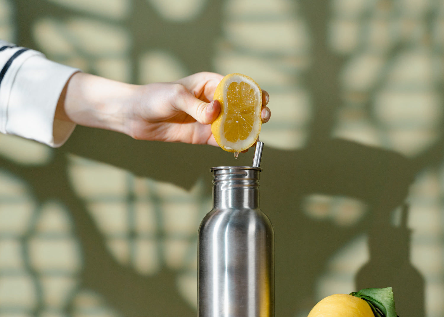Hand squeezes a lemon into a reusable water bottle