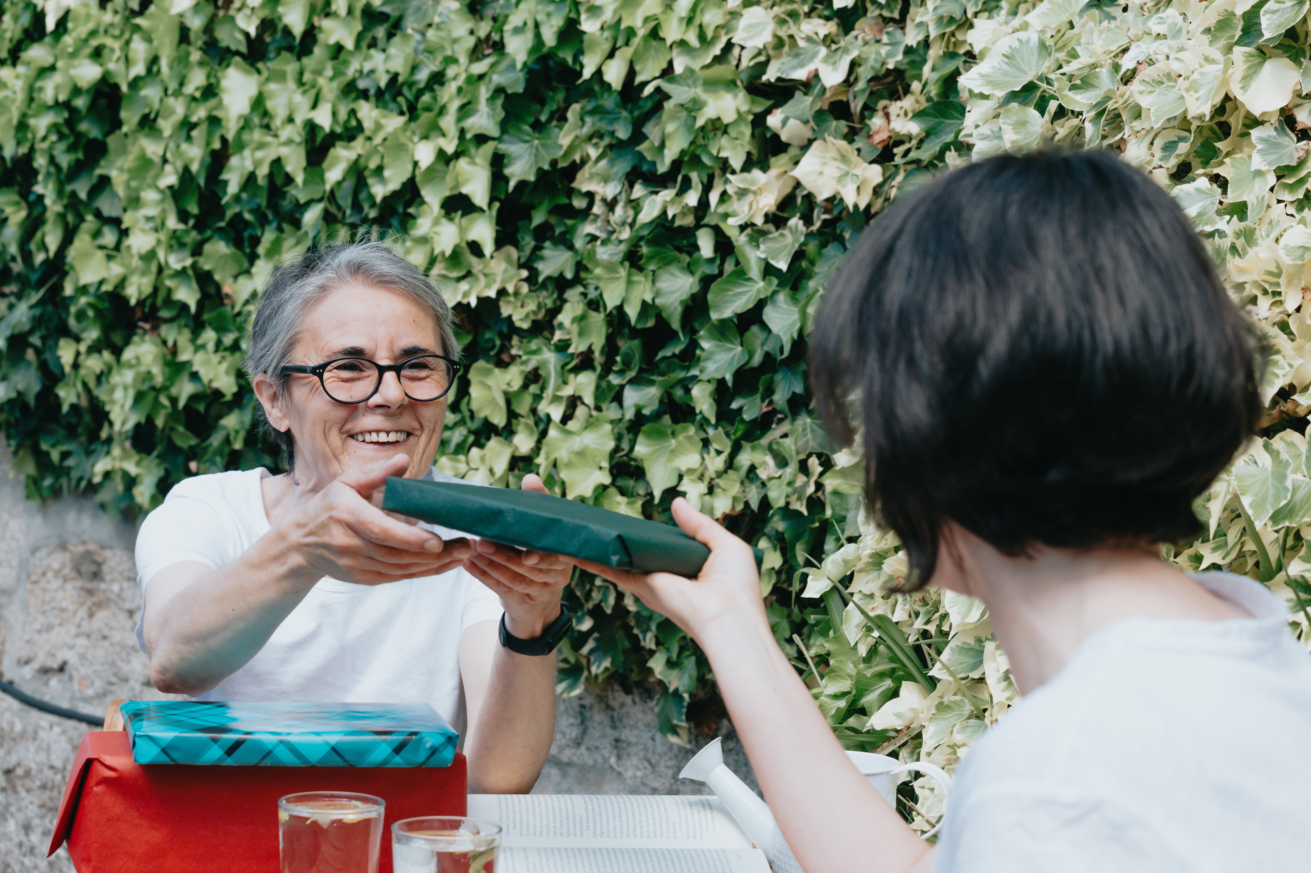 Two people having lunch on a patio exchange wrapped gifts