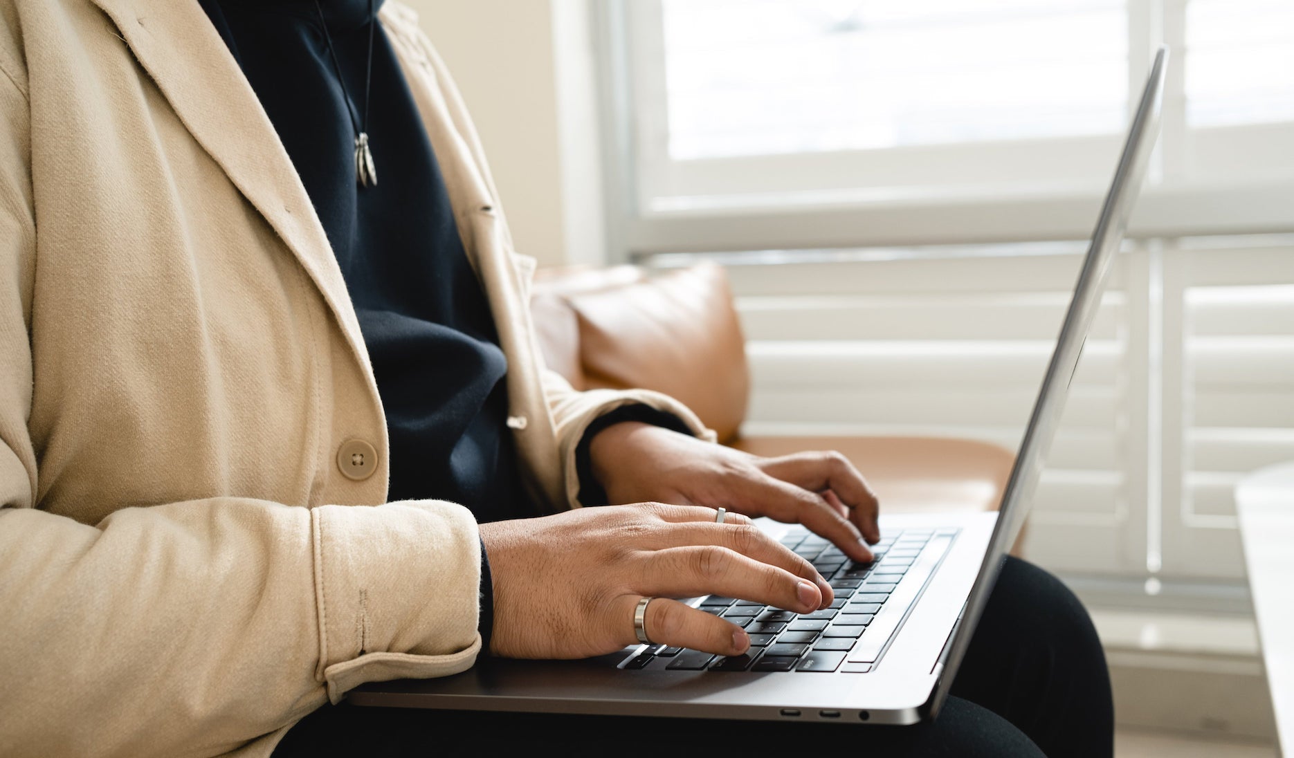 A woman in a brown coat typing on the computer