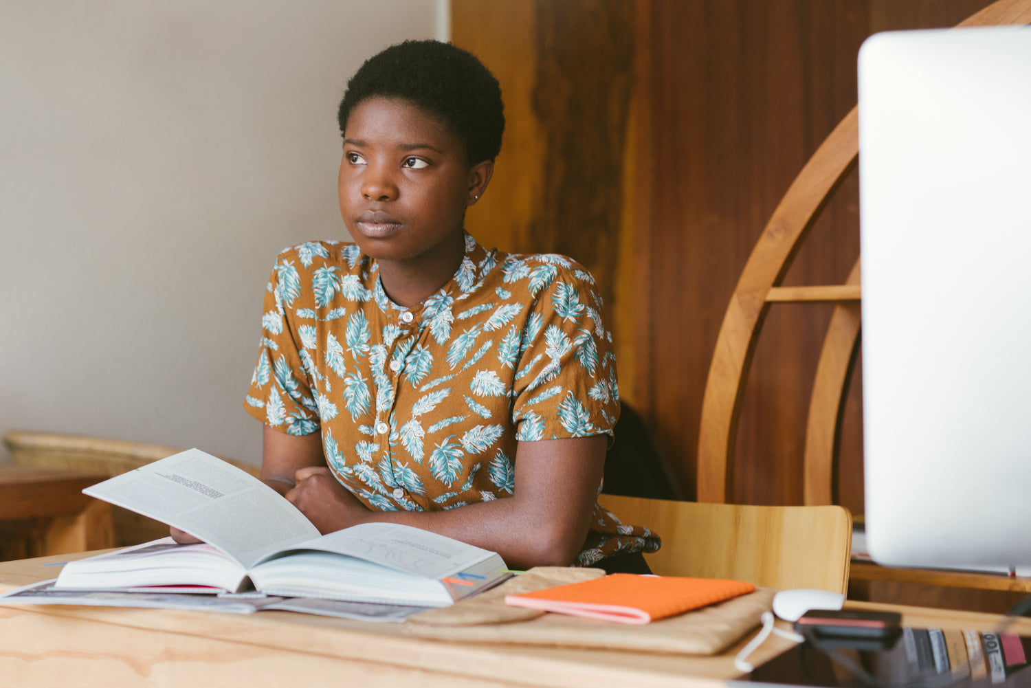 Woman looking pensive sits at a desk in front of an open book