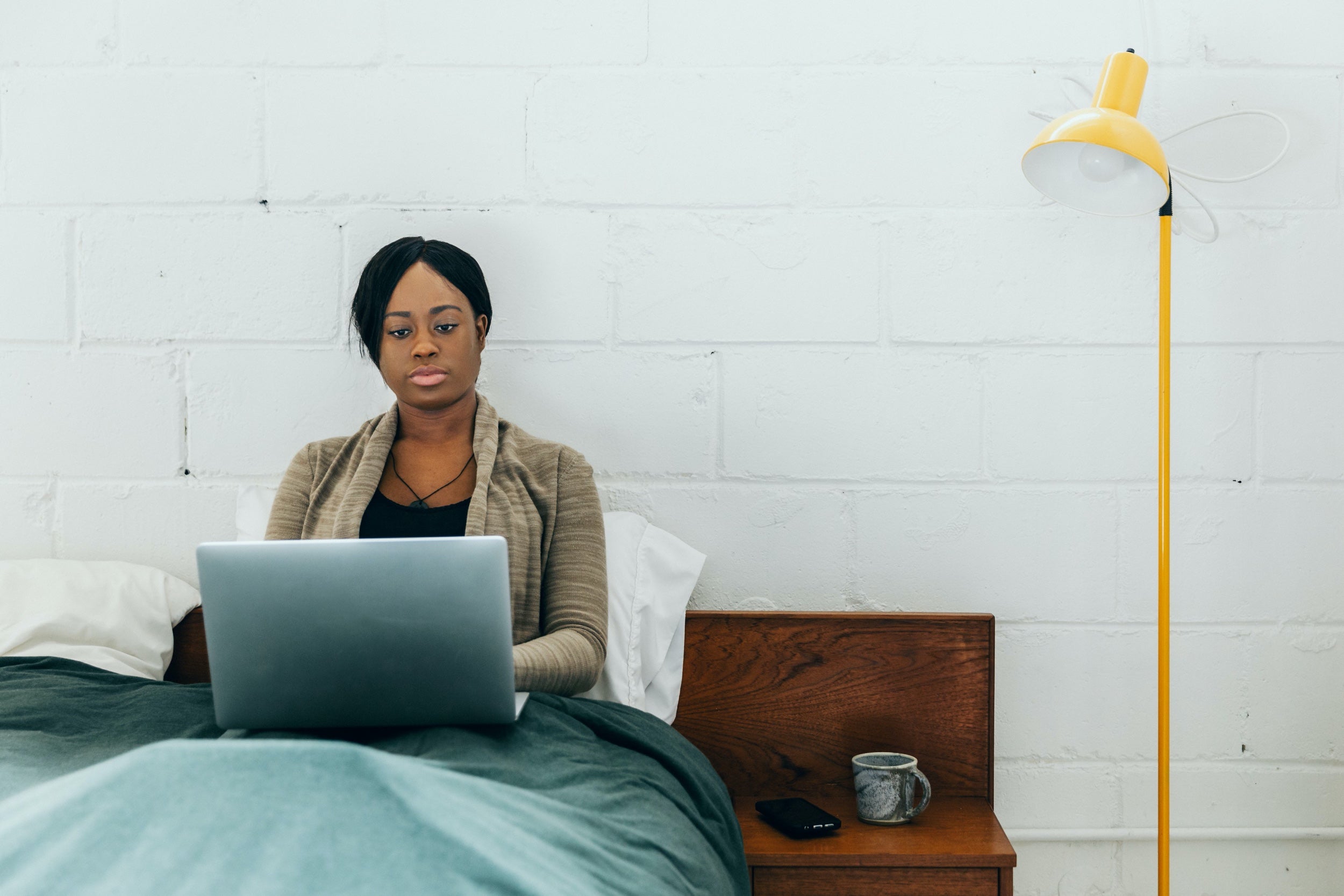 A woman works on a laptop in bed