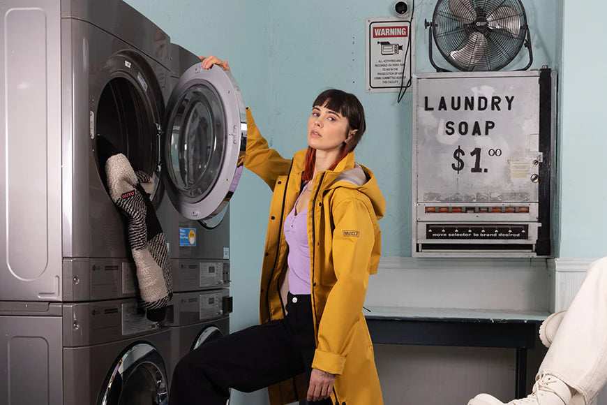 A woman models cruelty free outerwear in a laundromat