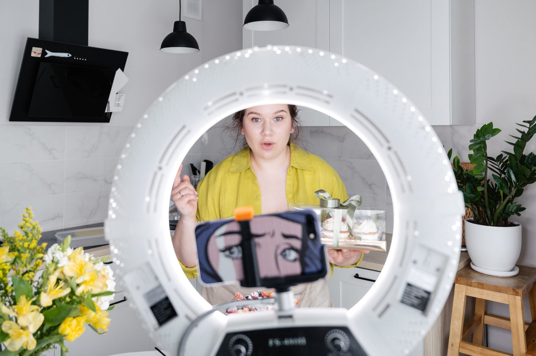 Young woman records a video using a phone and a ring light