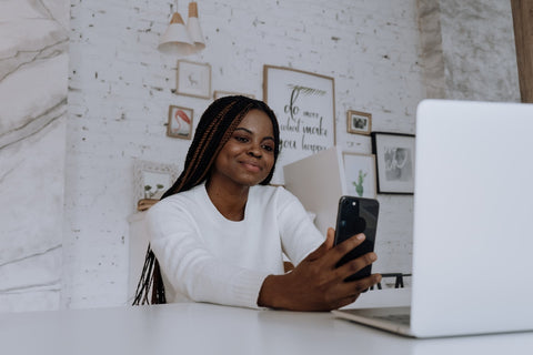 person holding phone and smiling looking as if they are taking a video