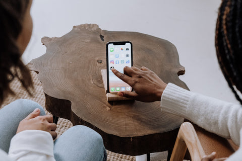 two people looking at a propped up phone and clicking on an app