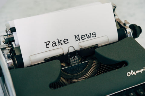 typewriter with paper that says fake news