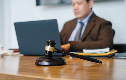 gavel in the forefront of a person typing on a computer using ai amazon listing creator