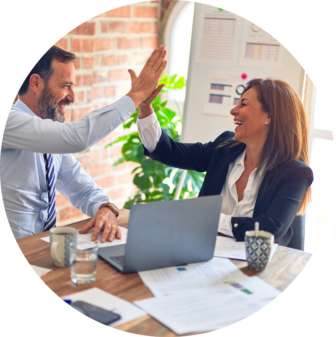 Two colleagues sitting in an office and high-fiving after optimizing Amazon listings