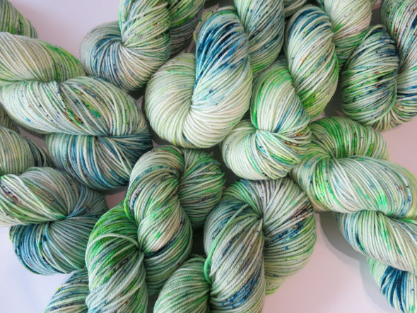 Skeins of green and blue yarn against a white background