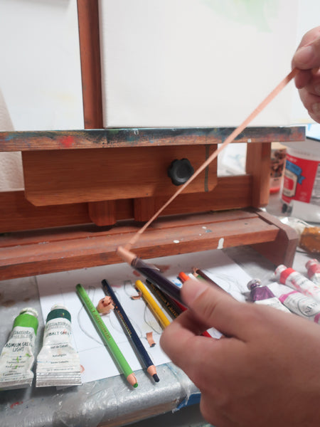 Ryan is peeling off the paper encasing of the color pencil.