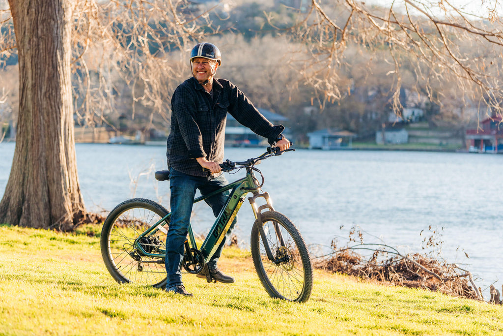 A man standing with the GOTRAX D1RT eMTB with front suspension and a torque sensor.