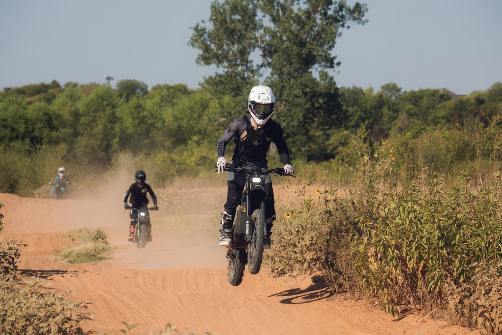 Three people coming down a trail one after another riding the GOTRAX Everest electric dirt bike with deep-tooth pneumatic tires and a 4000 watt rear wheel motor.