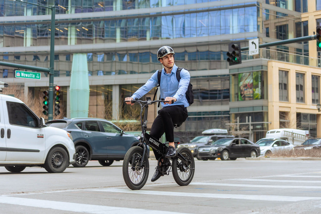 A man riding the GOTRAX F1 Folding Electric Bike with an adjustable seat down a city street.