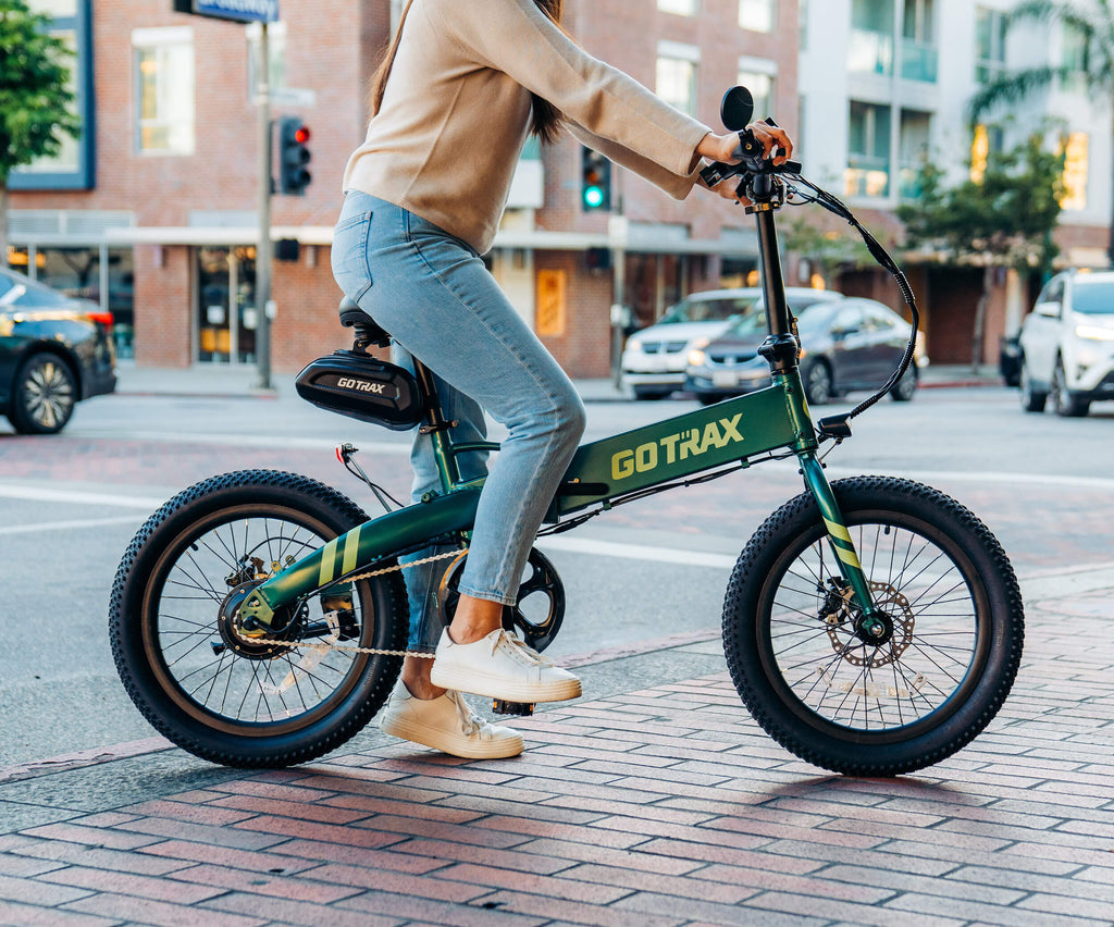 A woman riding the GOTRAX F1 V2 folding electric bike with a new larger battery.