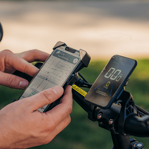 A closeup of a man using the GOTRAX F2 V2 folding electric bike's phone holder, one of five free accessories the bike comes with.