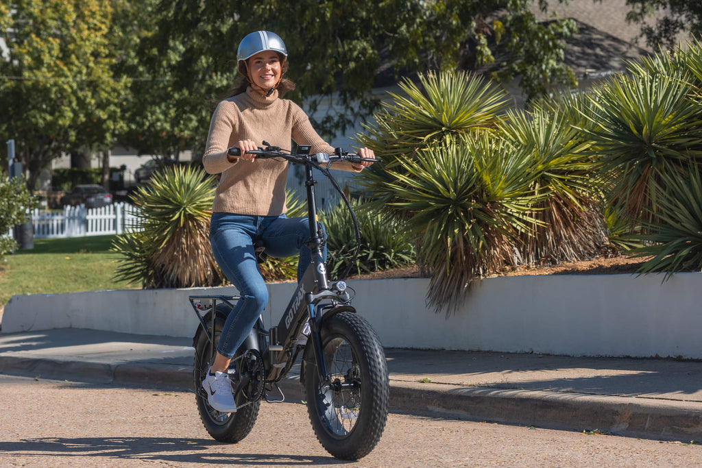 A woman riding the GOTRAX F3 foldable electric bike with fat tires and a rear cargo rack.