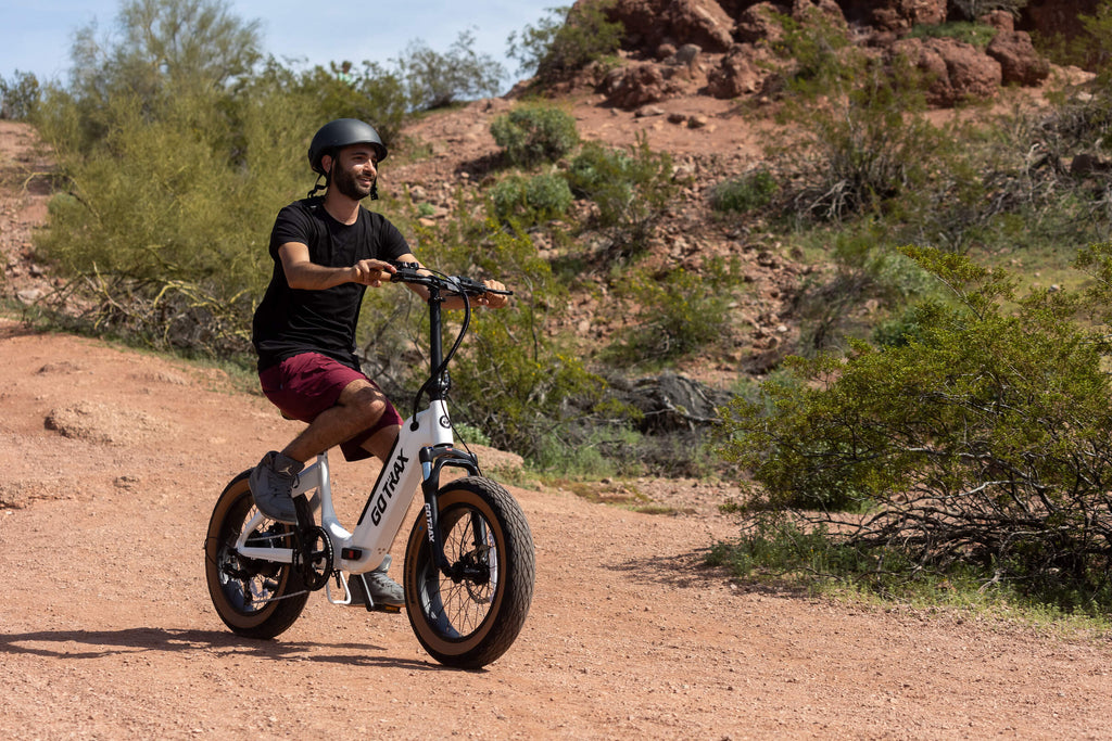 A rider using the GOTRAX F5 folding electric bike's pedal assist and fat tires to navigate an off-road path.