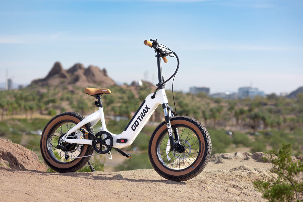 The GOTRAX F5 Folding Fat Tire Electric Bike parked on top of hilly desert terrain.