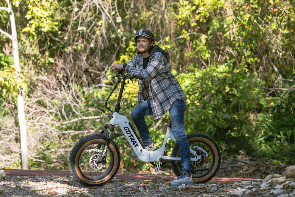 A man leaning on the GOTRAX F5 Folding Electric Bike with fat tires and hydraulic brakes.