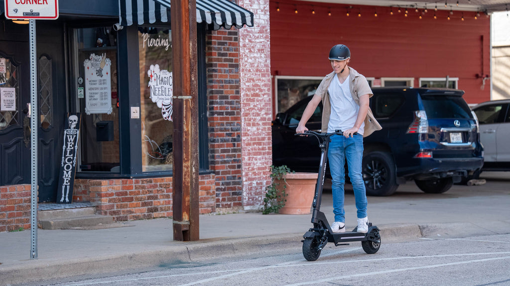 A man riding the GOTRAX GX1 dual motor electric scooter with dual suspension and dual braking.