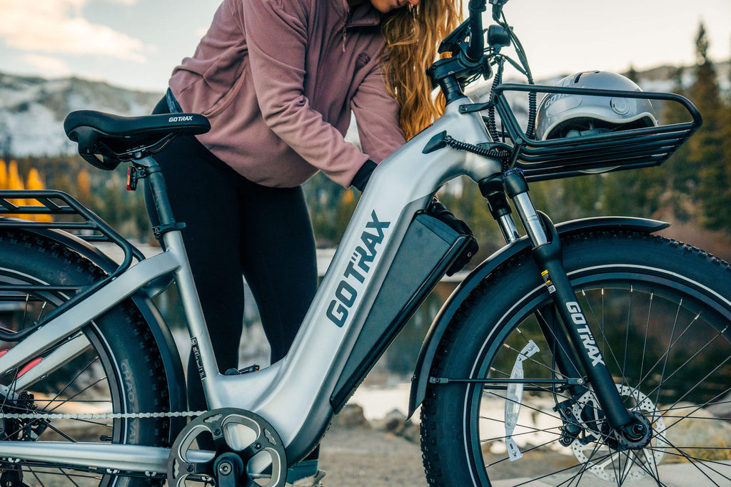 A woman checking the removable battery on a GOTRAX Fat Tire Electric Bike.