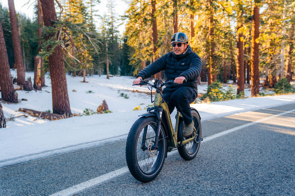 A man riding down a snowy road on the GOTRAX Tundra Fat Tire electric bike with a 33% longer range and torque sensor.