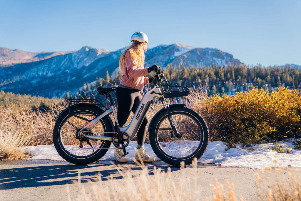 A woman standing with the GOTRAX Tundra Fat Tire Electric Bike in a step thru style.