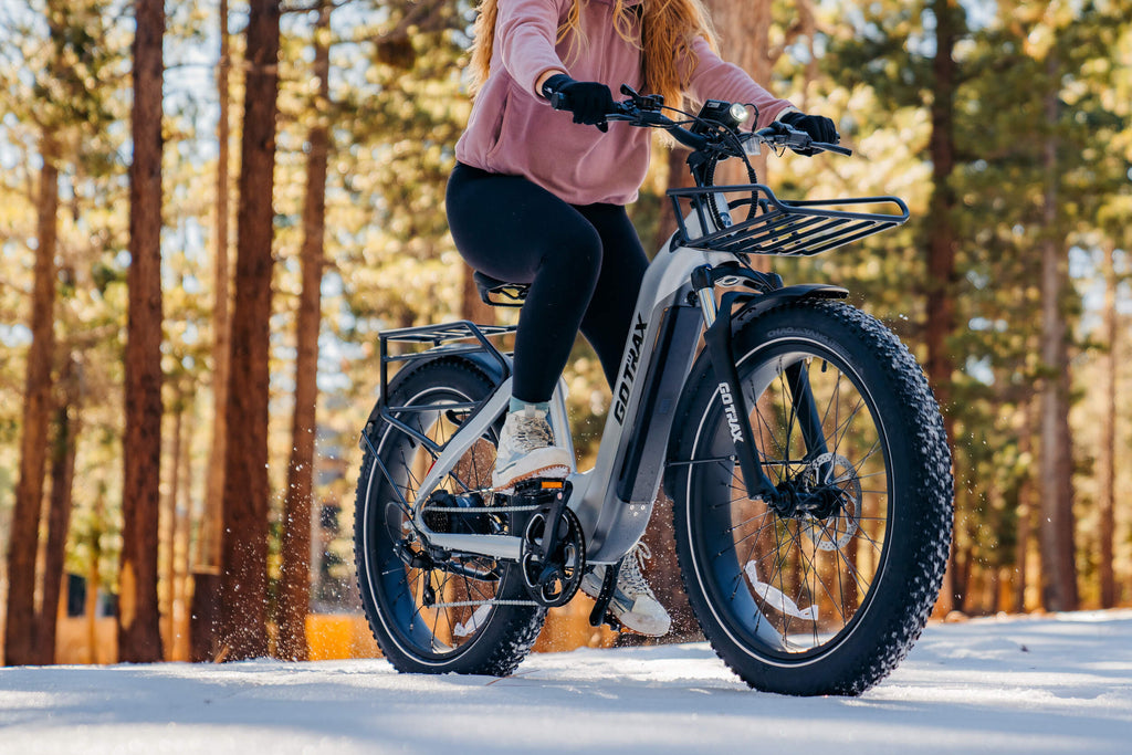 A woman riding a GOTRAX Tundra fat tire electric bike with front and rear storage rack compatability.